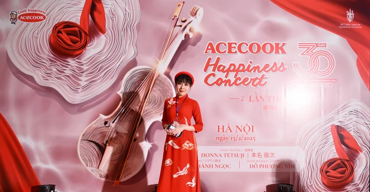 Christy in a red áo dài in front of an Acecook Happiness Concert backdrop